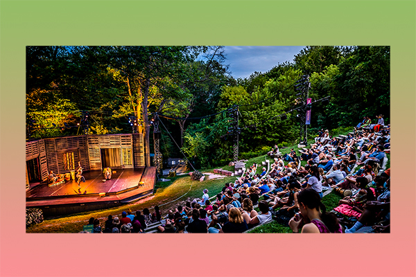 performers on outdoor stage with full seated audience.