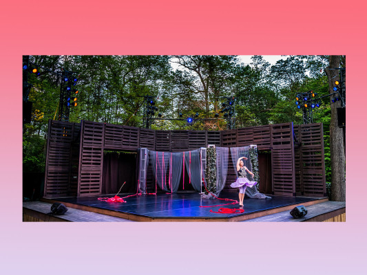 full view of outdoor stage with female dancer on stage left