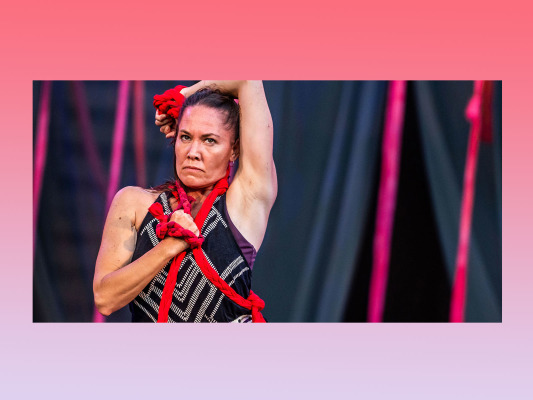 fierce look from close-up view of female dancer with red rope wrapped around body