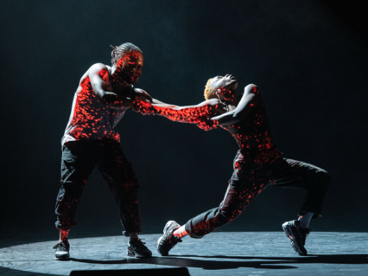 A duet of two dancers with blood-red projections splattering their bodies.