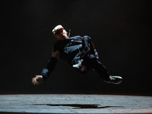 B boy Vibz has massive air between him and the stage as he's breaking.