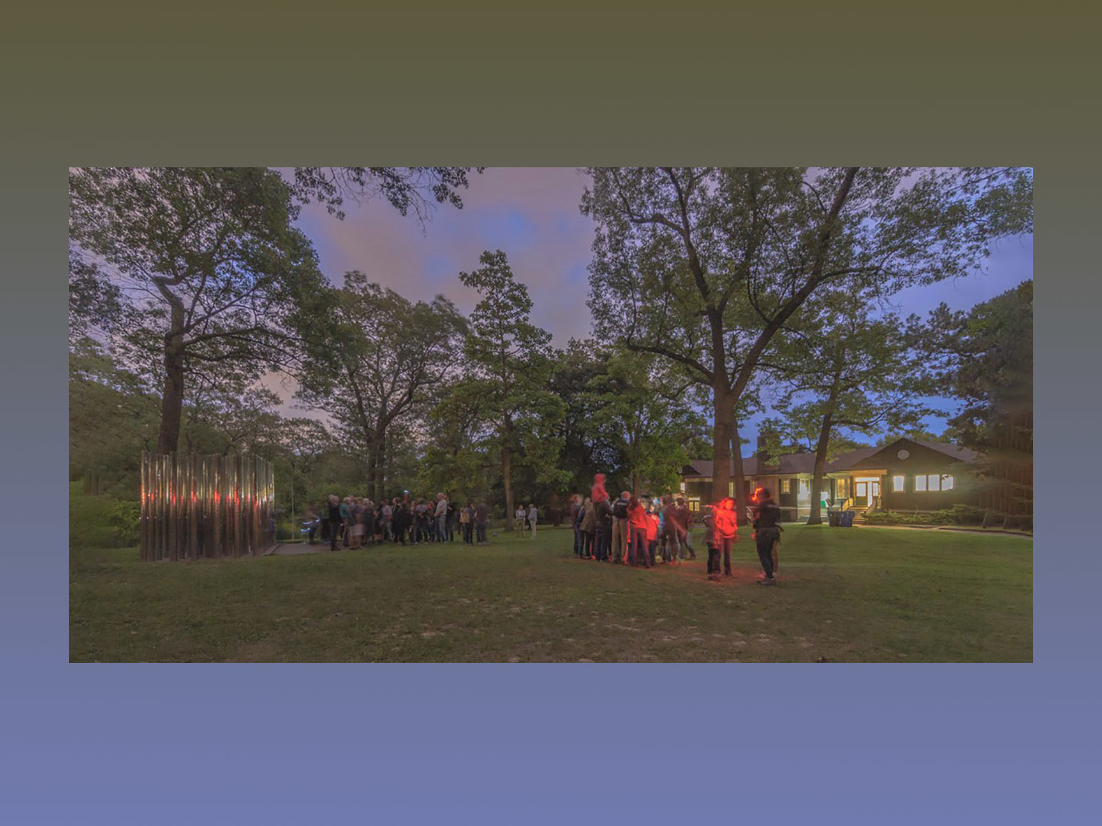 groups of people standing on a lawn at dusk