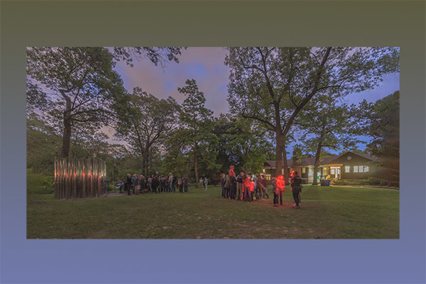 group of people standing on a lawn at dusk