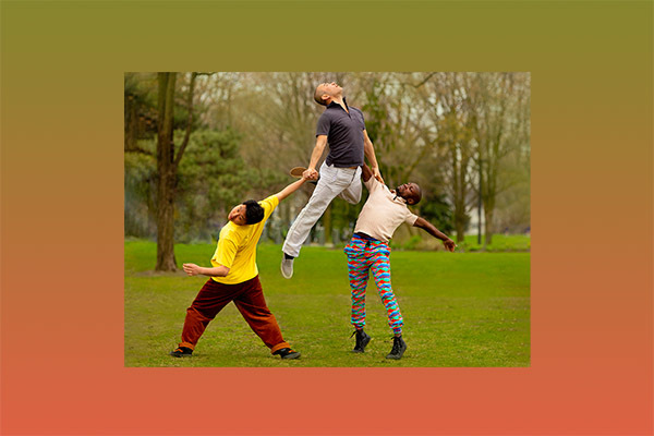 three men dancing in a park