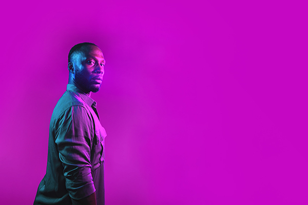 a man in front of a neon purple backdrop