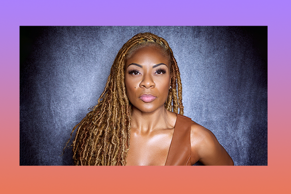 Jully Black in front of a dark backdrop staring into the camera.