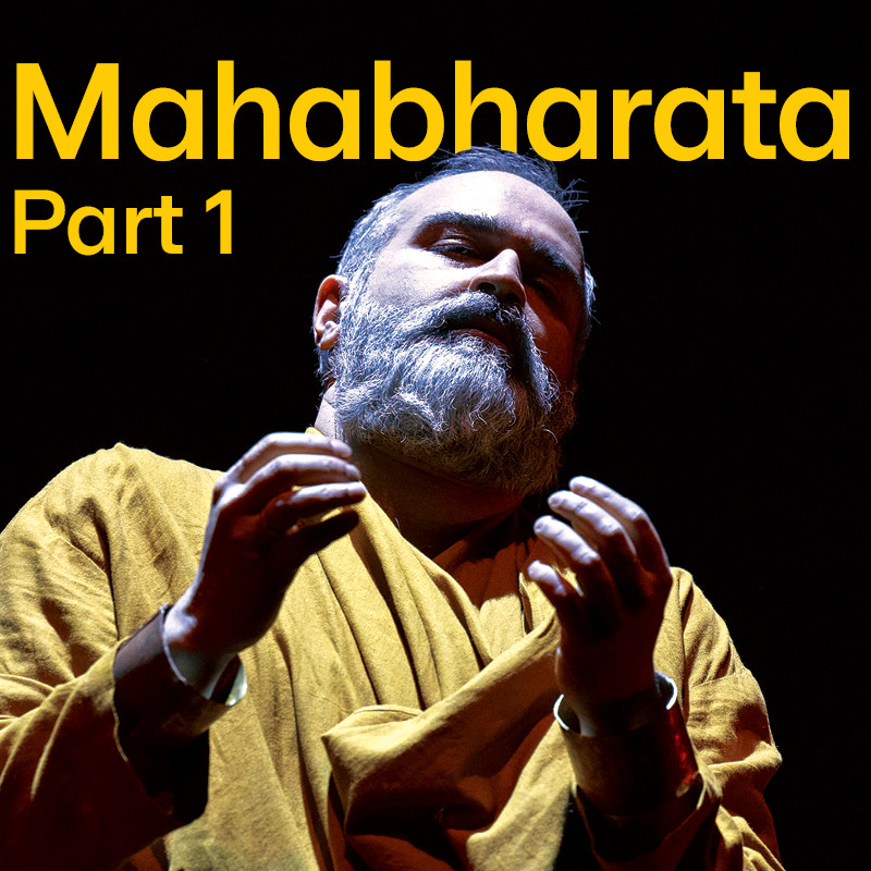 A man wearing a mustard coloured South Asian garment, with short hair and beard and both hands lifted. Yellow text reads, 